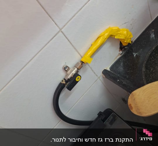 צינור גז עם סרט צהוב על קיר מטבח
